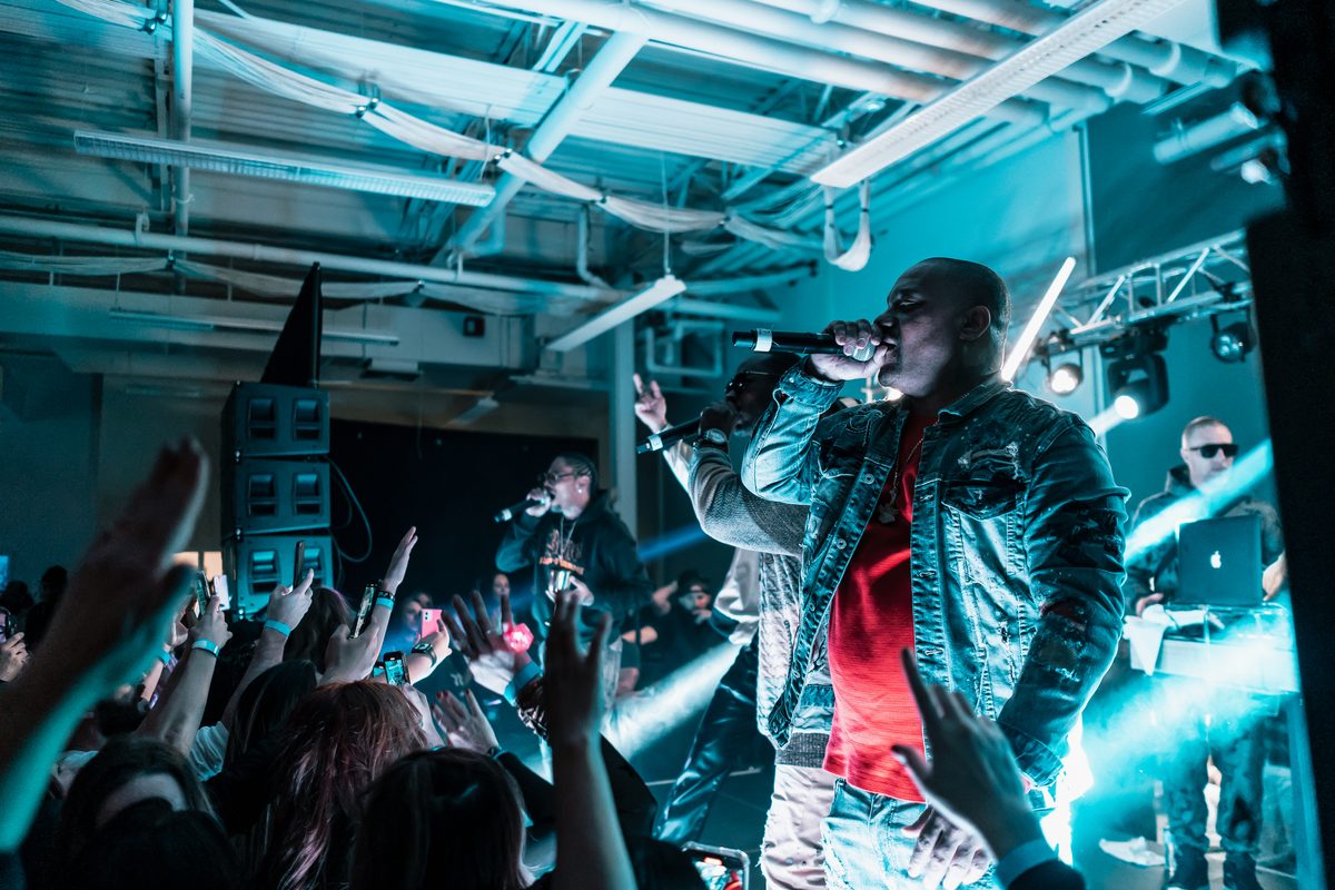 Artist performing over the crowd with a line array and teal stage lighting