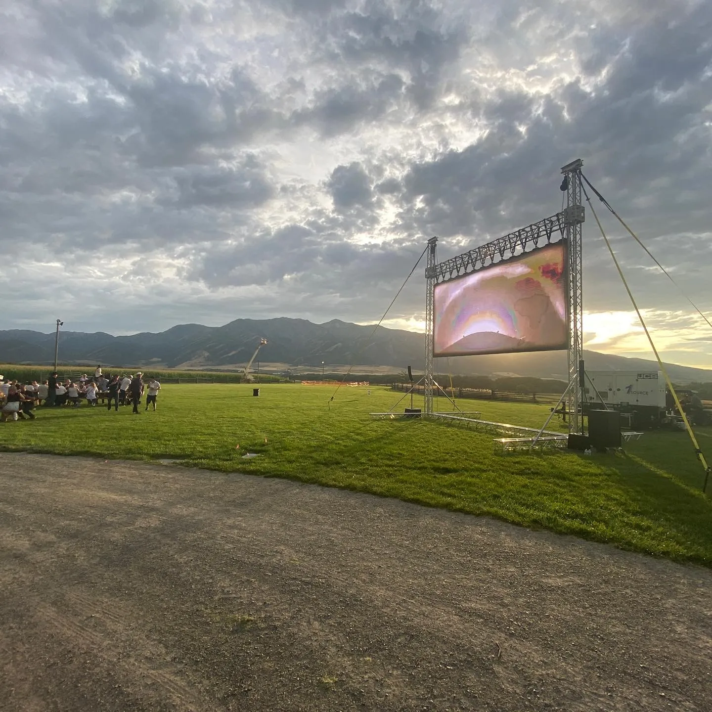 Large outdoor screen and PA set up in an open field at sunset for a Reeverb Entertainment event