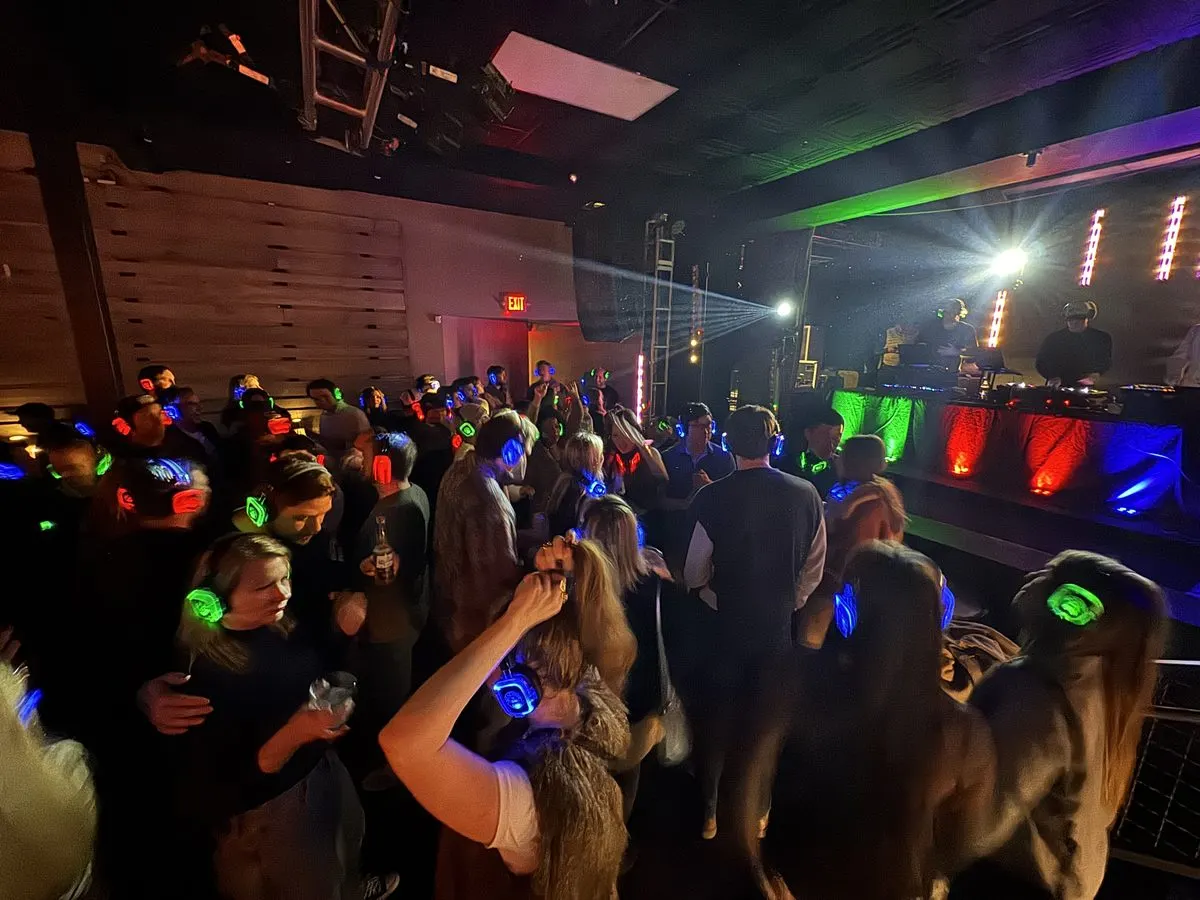 Crowd dancing at a Reeverb Entertainment silent disco with red, green, and blue LED headphones