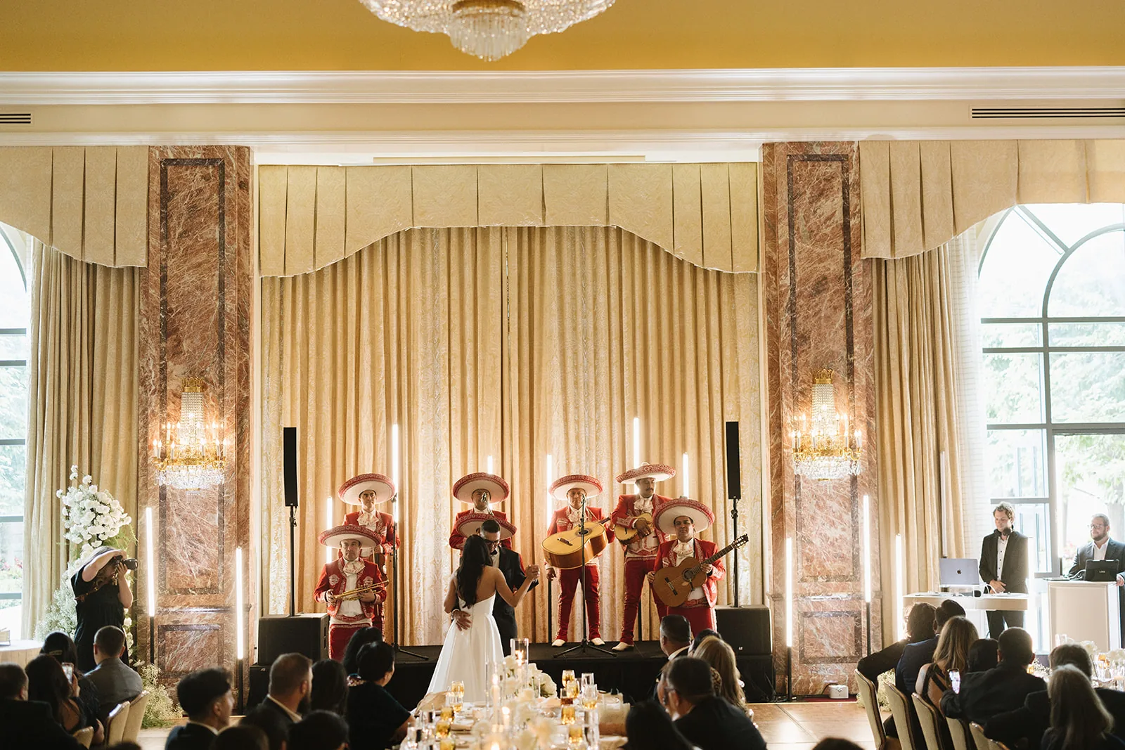Ballroom stage sound and lighting with a live band, vertical LED tubes, and speakers flown beside the proscenium