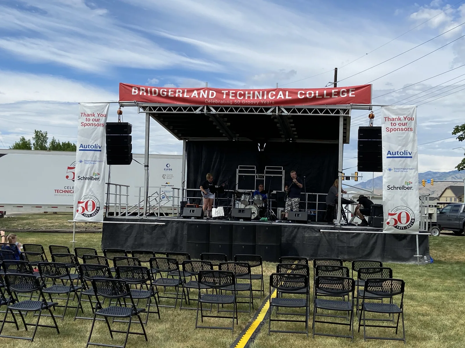 Outdoor mobile stage with flown line array sound and sponsor banners set for a live band