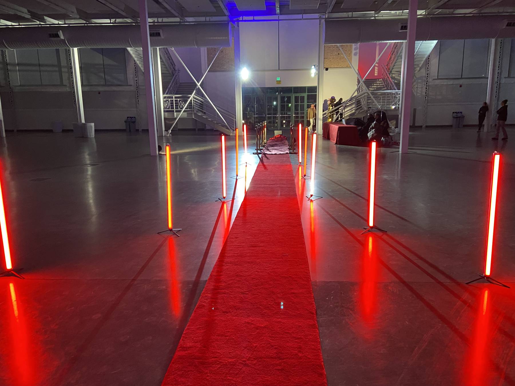 Red carpet lined with glowing red Titan tubes in a large venue